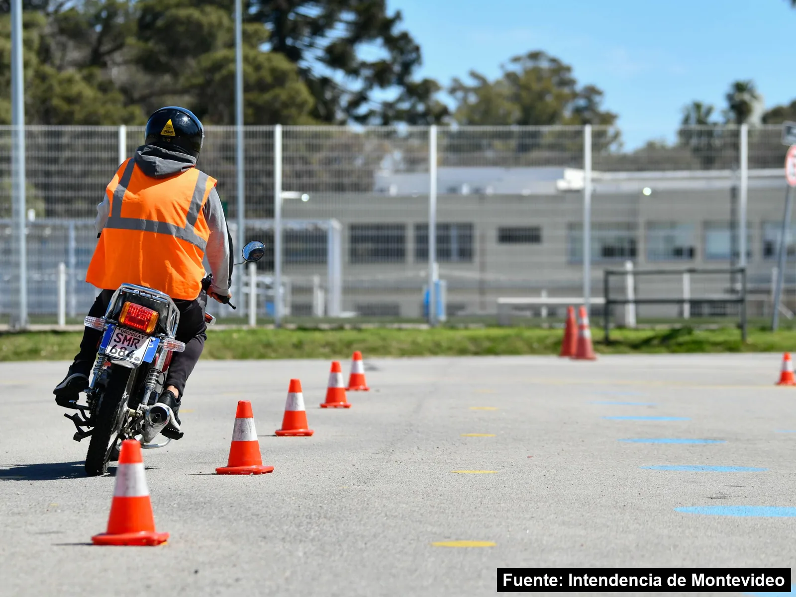 Un motociclista con chaleco naranja practica un recorrido entre conos en un taller del Centro de Educación Vial
